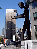 X is the Hammering Man (allowed as the sculpture is PD per UR1 and UR2). Simply including other things around X does not qualify as de minimis.