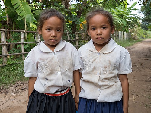 Twin sisters wearing their school uniform in the countryside of Don Som
